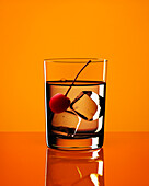 Longdrink with cherry and ice cubes with yellow background, Cocktail, Drink
