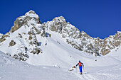 Woman back-country skiing ascending to Col Sautron, Monte Sautron in background, Col Sautron, Valle Maira, Cottian Alps, Piedmont, Italy