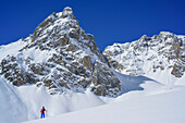 Woman back-country skiing ascending to Col Sautron, Monte Sautron in the background, Col Sautron, Valle Maira, Cottian Alps, Piedmont, Italy