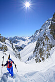 Woman back-country skiing ascending to La Forcellina, Monte Viraysse in the background, Col Sautron, Valle Maira, Cottian Alps, Piedmont, Italy