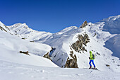 Woman back-country skiing looking towards Monte Salza, Monte Salza, Valle Varaita, Cottian Alps, Piedmont, Italy