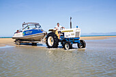 Taxiboote werden mit Traktor und Anhänger aus dem Meer geholt. Abel Tasman National Park, Südinsel, Neuseeland