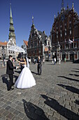 Hochzeitspaar tanzt auf Rathausplatz, Schwarzhaeupterhaus rechts aus dem 14. Jhdt, Gildehaus der unverheirateten Kaufleute, links St. Petri Kirche von 1209, Altstadt, Zentrum, Riga, Lettland
