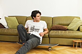 Young man leaning against the sofa, pensive