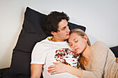 Young couple relaxing on the sofa, Hugging, Pensive