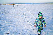 Boy walking in the snow, Cuxhaven, North Sea, Lower Saxony, Germany