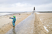 Boy pointing to North Sea, path to Kugelbake, Cuxhaven, North Sea, Lower Saxony, Germany