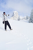 Snowboardfahrer geht durch Schneelandschaft, Kampenwand, Alpen, Bayern, Deutschland