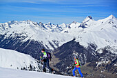 Two persons back-country skiing ascending towards Piz Arpiglia and Piz Uter auf, Piz Ueertsch and Piz Blaisun in background, Piz Arpiglia, Livigno Alps, Engadin, Grisons, Switzerland