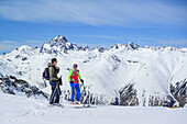 Two persons back-country skiing standing at Piz Uter, Piz Kesch in background, Piz Uter, Livigno Alps, Engadin, Grisons, Switzerland