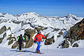 Two persons back-country skiing ascending towards Dreiherrnspitze, Gabler and Reichenspitze in background, Dreiherrnspitze, valley of Ahrntal, Hohe Tauern range, South Tyrol, Italy