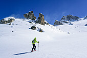 Woman back-country skiing ascending towards Colle di Vers, Rocca La Marchisa in the background, Colle di Vers, Valle Varaita, Cottian Alps, Piedmont, Italy