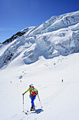 Frau auf Skitour steigt zur Punta San Matteo auf, Gletscherbruch im Hintergrund, Punta San Matteo, Val dei Forni, Ortlergruppe, Lombardei, Italien