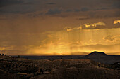 Gelbe Sonnenstrahlen durchbrechen Wolken, Gewitterstimmung über der ebene von Granada von Monachil am Fuss der Sierra Nevada gesehen, Andalusien, Spanien, Europa