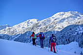 Three persons back-country skiing ascending towards Pallspitze, Pallspitze, Langer Grund, Kitzbuehel range, Tyrol, Austria