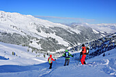 Three persons back-country skiing downhill from Pallspitze, Pallspitze, Langer Grund, Kitzbuehel range, Tyrol, Austria