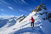 Woman back-country skiing ascending towards Monte Soubeyran, in background Tete Peymian, Punta della Reculaye and Aiguille de Barsin, Monte Soubeyran, Valle Maira, Cottian Alps, Piedmont, Italy
