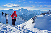 Woman back-country skiing standing at summit of Monte Soubeyran and looking towards Cottian Alps, Monte Soubeyran, Valle Maira, Cottian Alps, Piedmont, Italy