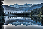 Lake Matheson reflection with predawn winter light on Mount Tasman and Mount Cook, near Fox Glacier, Westland National Park, New Zealand