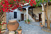 Red bougainvillea flowers in the yard of a stone building at the Folklore museum in Geroskipou near Nea Paphos, Paphos, Cyprus