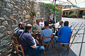 Men sitting at bar tables along the road in Gourri village about 30km westl of Lefkosia, Nicosia, Cyprus