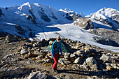 Woman hiking with view to Piz Palue (3905 m), Bellavista (3922 m), Piz Bernina (4049 m) and Pers glacier, Engadin, Grisons, Switzerland