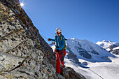 Woman climbing the via ferrata at Piz Trovat with view to Piz Palue (3905 m), Bellavista (3922 m) and Pers glacier, Engadin, Grisons, Switzerland