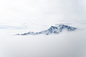 The massif of Monte Rosa protruding through the clouds, with the Margherita Hutas a tiny black spot on the summit of Signalkuppe or Punta Gnifetti, Pennine Alps, canton of Valais, province of Verbano-Cusio-Ossola, Switzerland and Italy