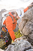 Eine junger Kletterer klettert am Ausstieg der Route namens Silvesterroute, Klettergebiet Brüggler, Glarner Alpen, Kanton Glarus, Schweiz