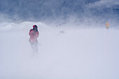 Ein Skitourengänger mit einer Spiegelreflexkamera fotografiert im Föhnsturm, Gipfel des Mattjisch Horn, Hochtal Fondei, Bündner Alpen, Kanton Graubünden, Schweiz