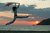 Young woman jumping on a beach, Crete, Greece