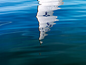 Reflection of a sailboat on lake Chiemsee, Bavaria, Germany