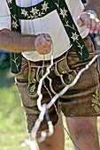 Man wearing traditional clothes pulling a wire, Viehscheid, Allgau, Bavaria, Germany