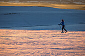Young woman cross-country skiing at sunset, Allgauu, Bavaria, Germany