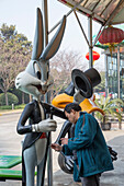 Mann gibt einer Bugs Bunny Figur in einem Vergnügunspark einen neuen Anstrich, Shanghai, China, Asien