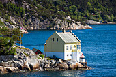 Yellow wooden house in fjord, near Bergen, Hordaland, Norway
