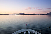 Bow of cruise ship MS Deutschland (Reederei Peter Deilmann) and coastline at dusk, near Lofoten, Norway