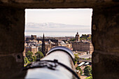 Cannon in opening of Edinburgh Castle with view of city, Edinburgh, Scotland, United Kingdom