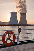 Lifering and railing of cruise ship MS Deutschland (Reederei Peter Deilmann) with Doel Nuclear Power Station on Scheldt river at sunset, near Antwerp, Flemish Region, Belgium
