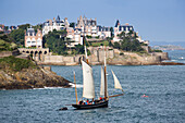 Excursion sailboat La Cancalaise (replica of 1905 French cutter Le Perle) during sailing excursion in Saint-Malo Bay with Dinard coastline behind, Dinard, Brittany, France
