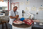 Metzger schneidet Fleisch in einer Metzgerei, Heraklion, Kreta, Griechenland, Europa
