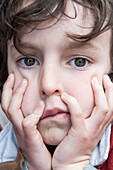 Boy resting chin in hands, bored expression on face