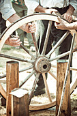 Craftsmen repairing horse-drawn wagon wheel