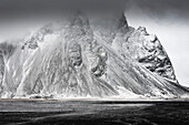 Dark clouds over winterly peninsula Stokksnes with mountain range Klifatindur and peak Vesturhorn (Vestrahorn), coastal flat plains near Hofn, East Iceland, Iceland, Europe