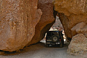 Jeep fährt durch Felsspalte im Scharyn Canyon, Scharyn Nationalpark, Region Almaty, Kasachstan, Zentralasien, Asien