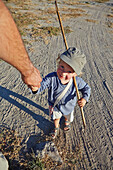 Junge geht an der Hand vom Vater in der Steppe, Kubu Island, Makgadikgadi Pans Nationalpark, Botswana