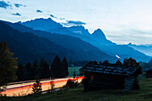 Landstraße nach Innsbruck mit Lichtstreifen, im Hintergrund Alpspitz, Zugspitze, Waxenstein und Sprungschanze, Garmisch-Partenkrichen, Oberbayern, Deutschland
