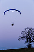 Motor-Gleitschirm und Mond in der Abenddämmerung, Penzberg, Oberbayern, Deutschland