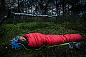 junge Frau im Schlafsack im Moorwald, Berg am Starnberger See, Oberbayern, Deutschland