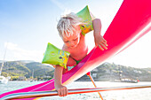 5 year old boy on a pink slide, Mediterranean Sea, MR, Port de Soller, Serra de Tramuntana, Majorca, Balearic Islands, Spain, Europe